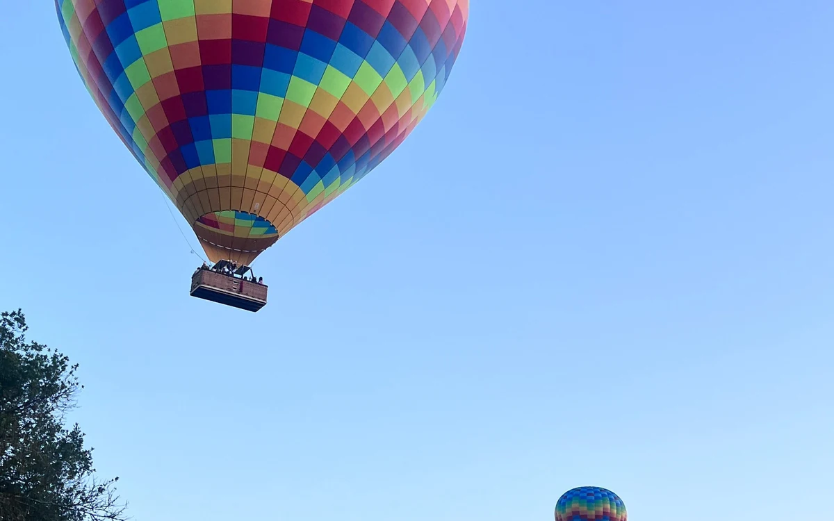 Dos globos a distintas alturas sobre el fondo de un valle con colinas detrás